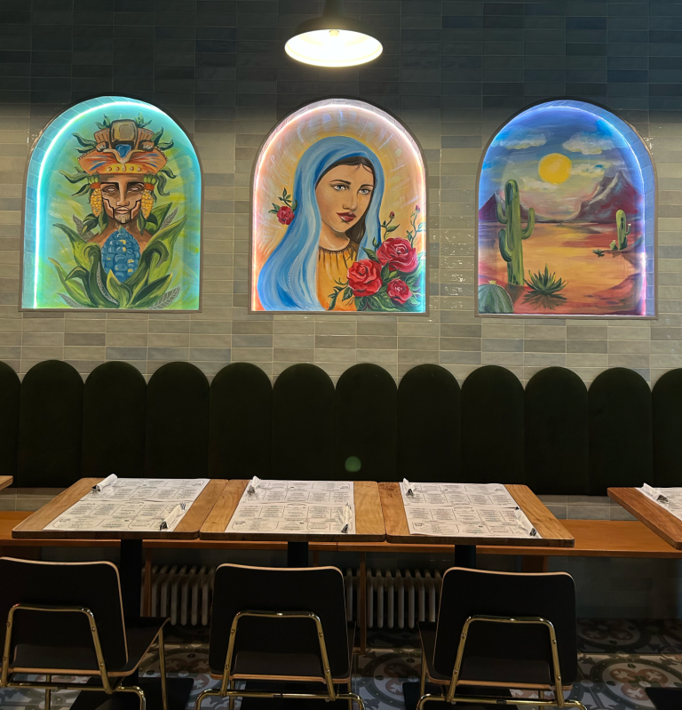 Bunte Wandmalereien von Pflanzen und Frauen mit Maria im Restaurantambiente.