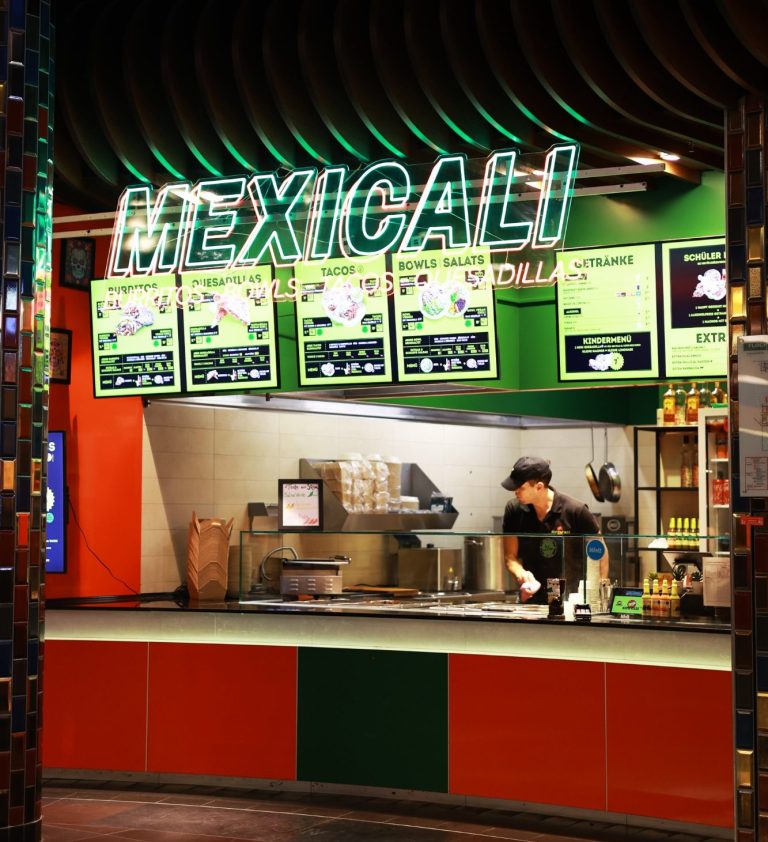 Mexican Fast-Food-Stand mit grüner Beleuchtung und Menütafeln.
